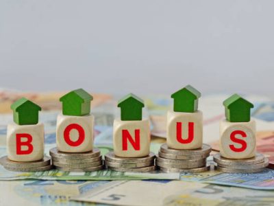 bonus fiscali 2024 quali requisiti Wooden house and blocks with the word Bonus on coins and banknotes - Concept of home renovation bonus